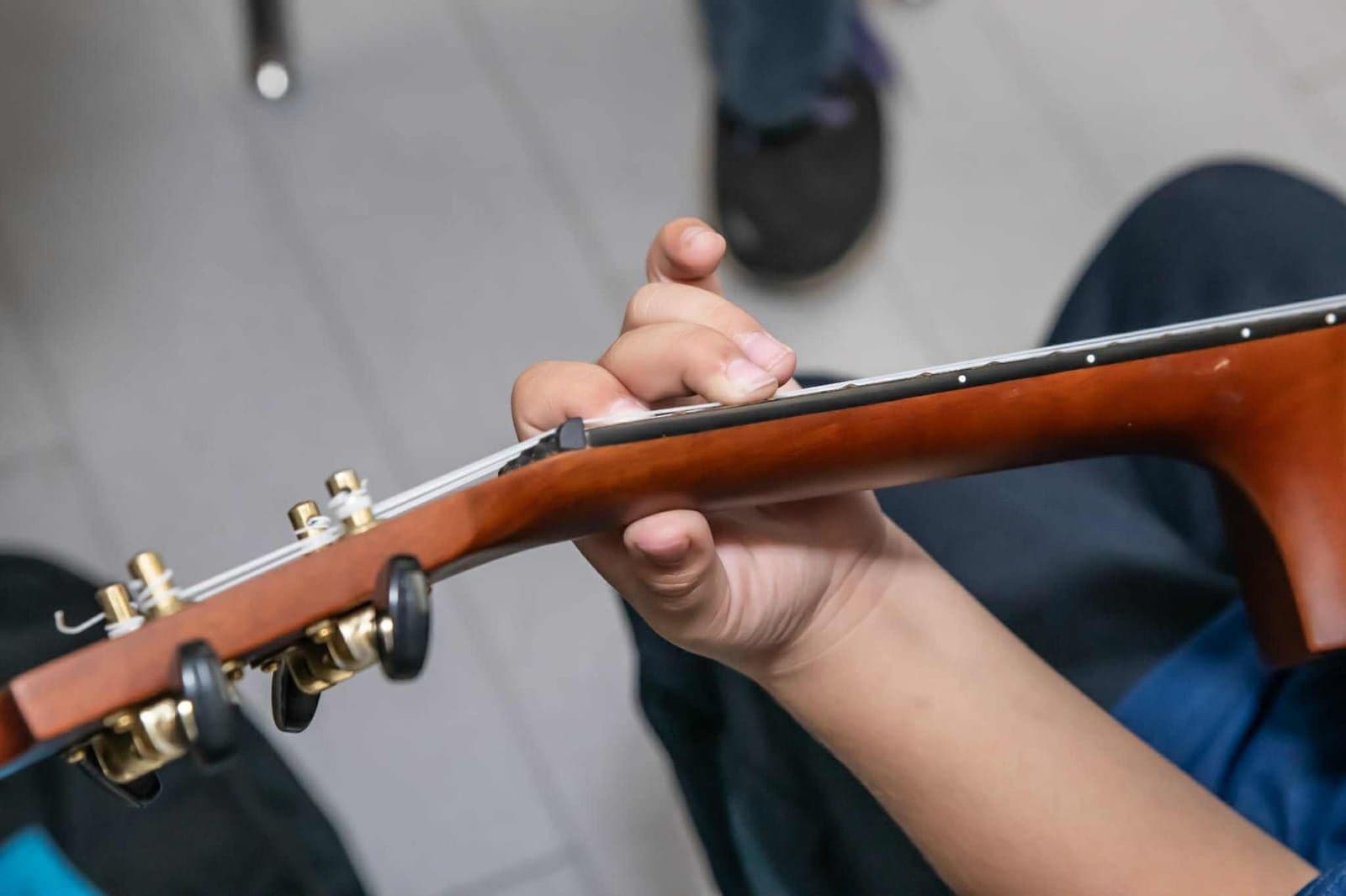 Overhead view of a student’s hand working through a chord on the fretboard