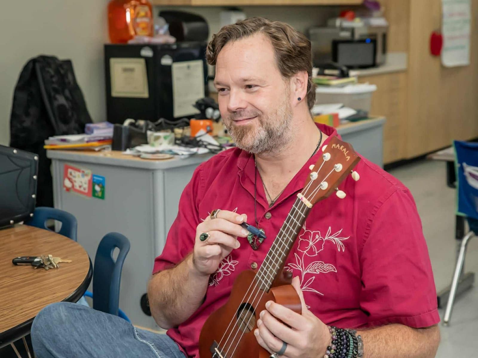 John Ford holds a ukulele and a clip-on tuner while talking to students