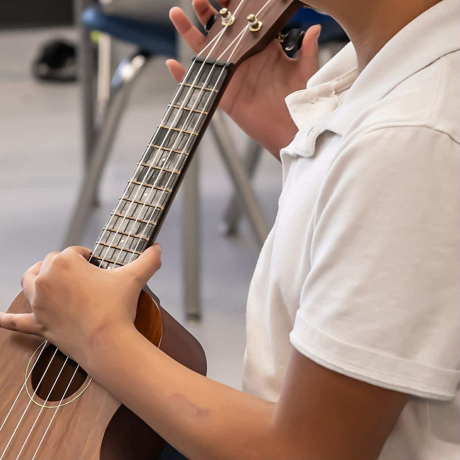 A student practices finger positions on the ukulele fretboard