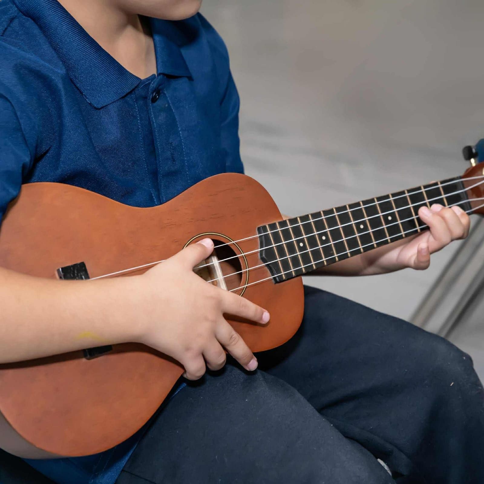 Close-up of a student’s hands strumming a ukulele