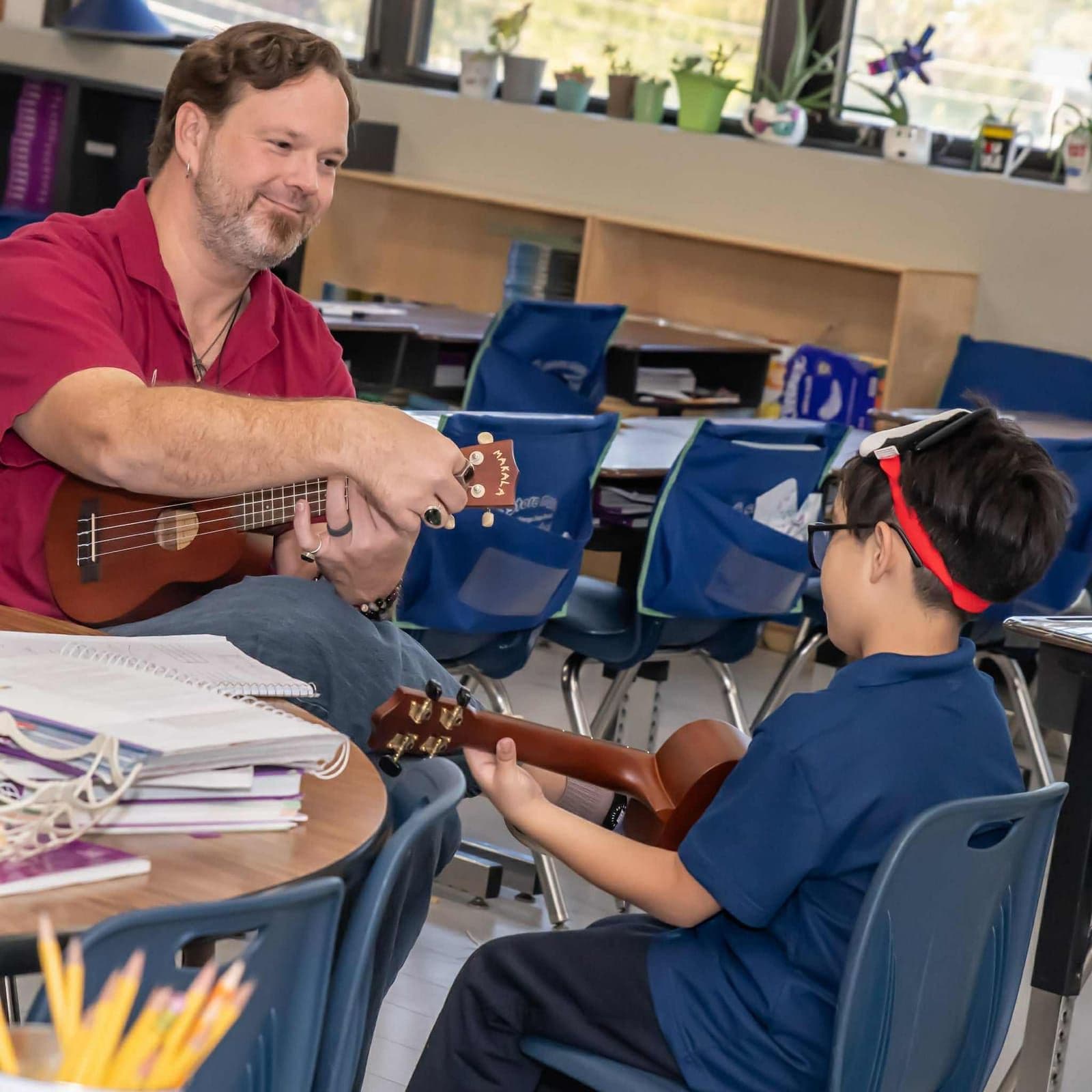Mentor John Ford tunes a ukulele while a student holds his own instrument