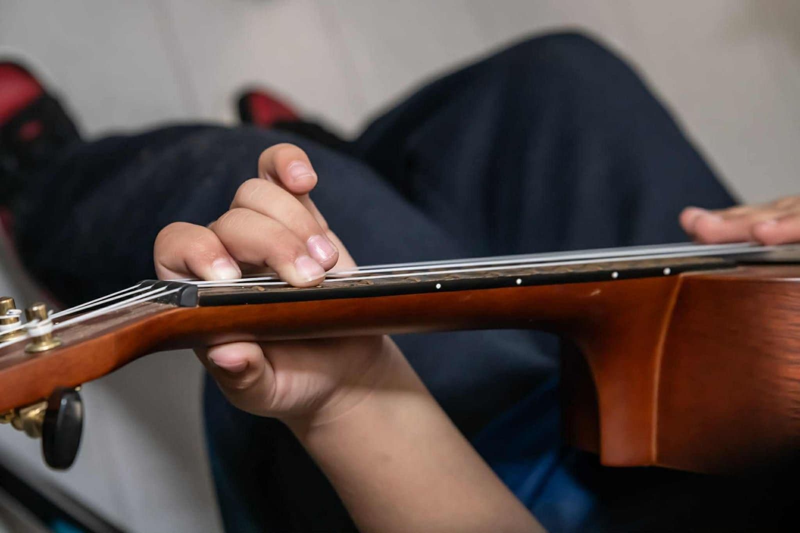 Close-up of a young student’s fingers pressing ukulele strings