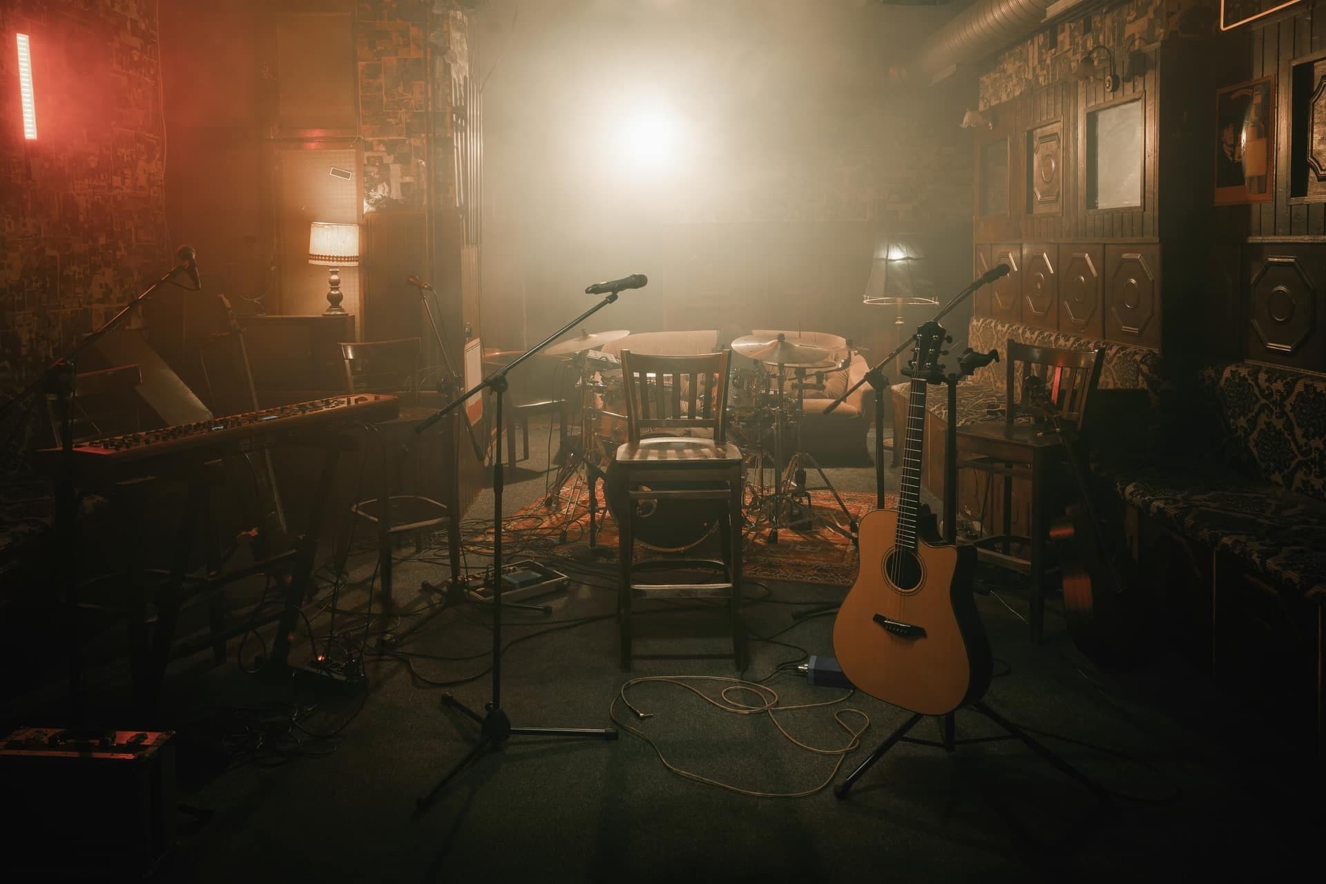 An acoustic guitar on a stand in a warmly lit music studio