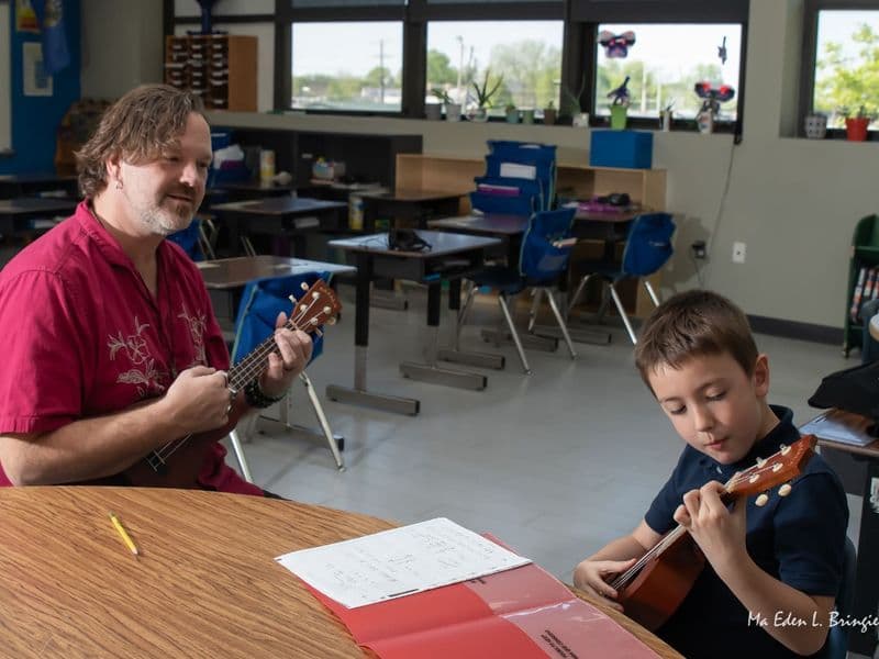 John Ford and a young student play ukulele together at a classroom table